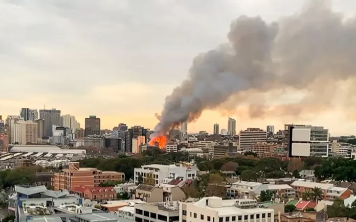 Thick smoke from the Sydney recycling plant fire spreads across the sky, raising environmental and health concerns.